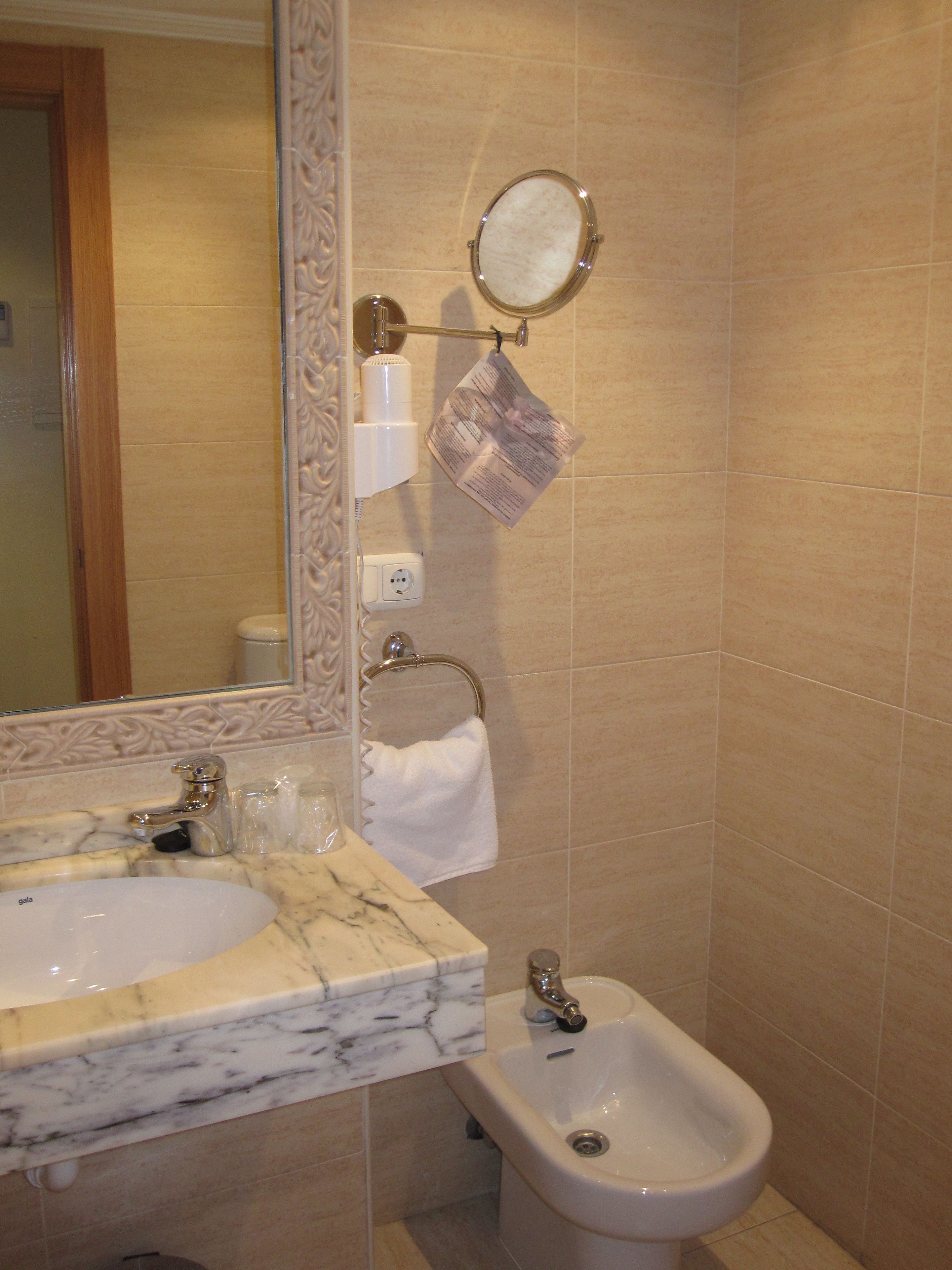 A bathroom with two sinks, a bidet, a mirror, and a towel rack.