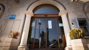 Entrada de un edificio con puerta de vidrio, columnas y un letrero que indica 'HR'.