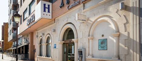 Fachada de hotel con un llamativo letrero con la letra 'H', que indica un hotel.