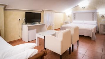 Una habitación de hotel con una cama, un escritorio con televisor, una silla y una mesita.
