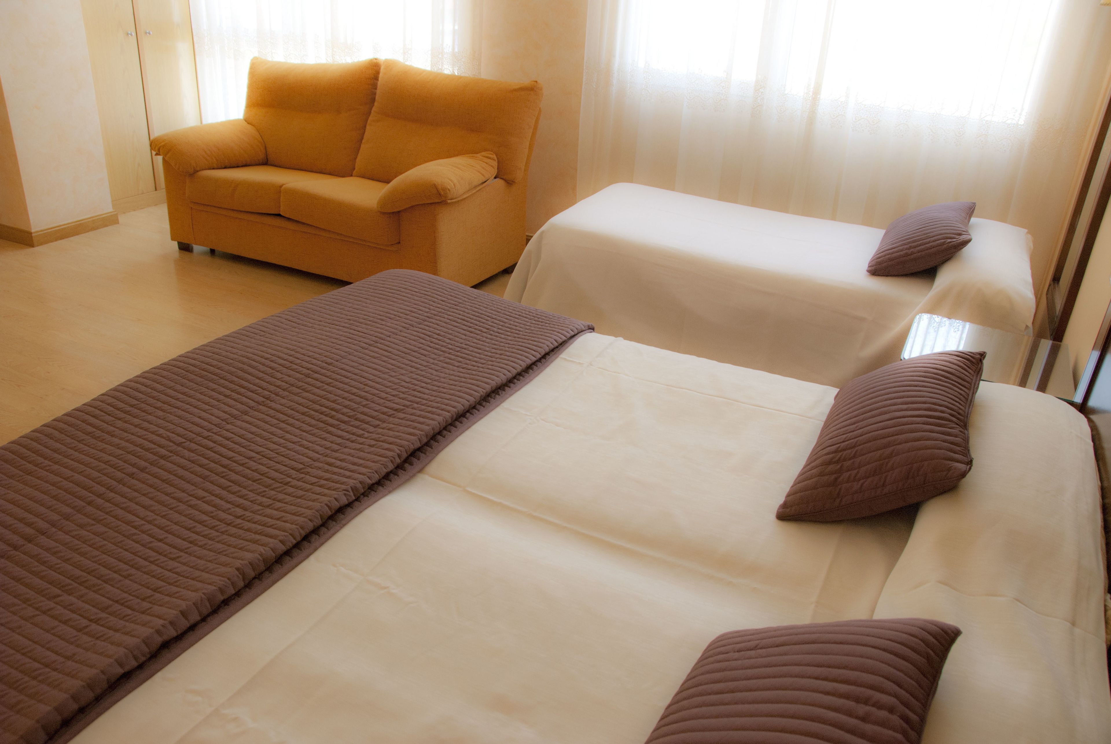 Quarto de hotel com uma cama grande, uma cama menor, um sofá e um guarda-roupa.