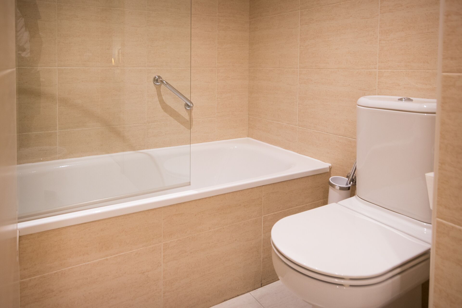 Een badkamer met een badkuip, toilet en een handgreep.