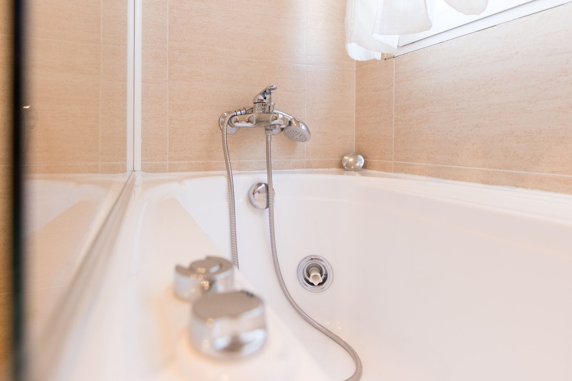 Una bañera con ducha de mano y grifo integrado.