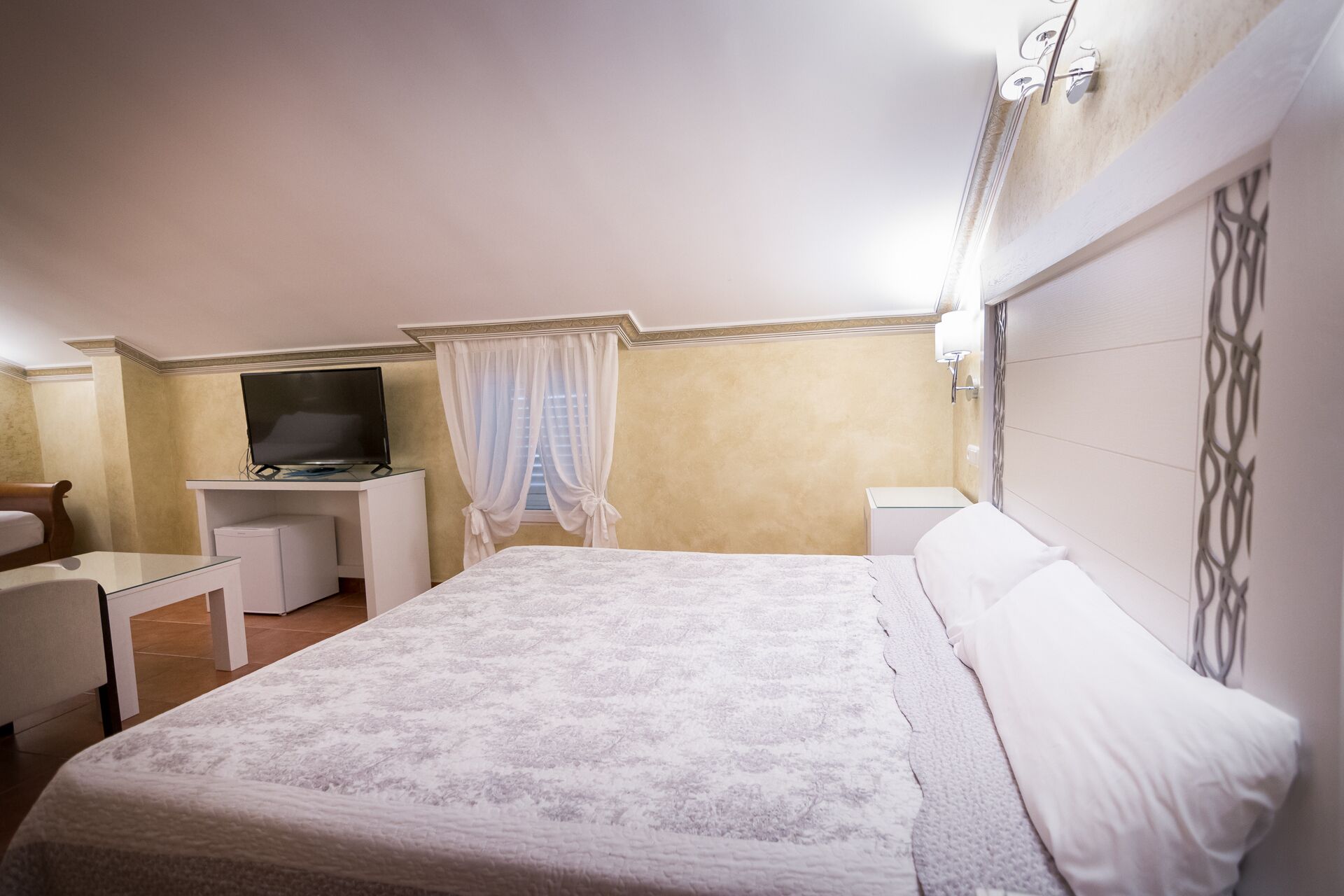 Une chambre d’hôtel équipée d’un lit, d’un bureau, d’une télévision et d’un petit coin salon.