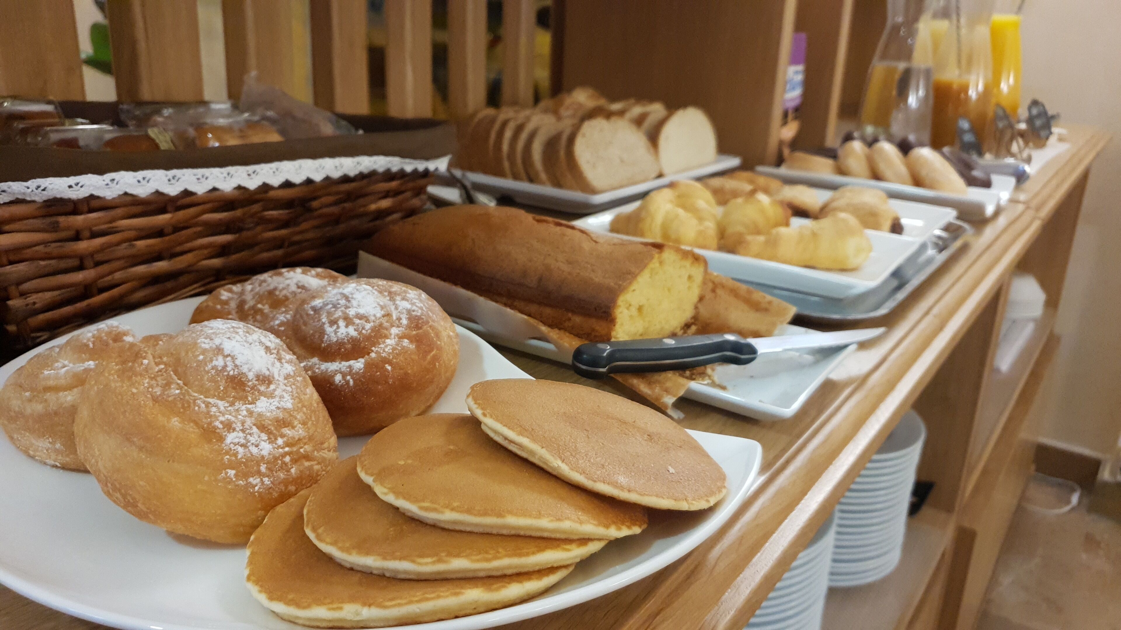 A buffet with various breakfast items including pastries, bread, and pancakes.