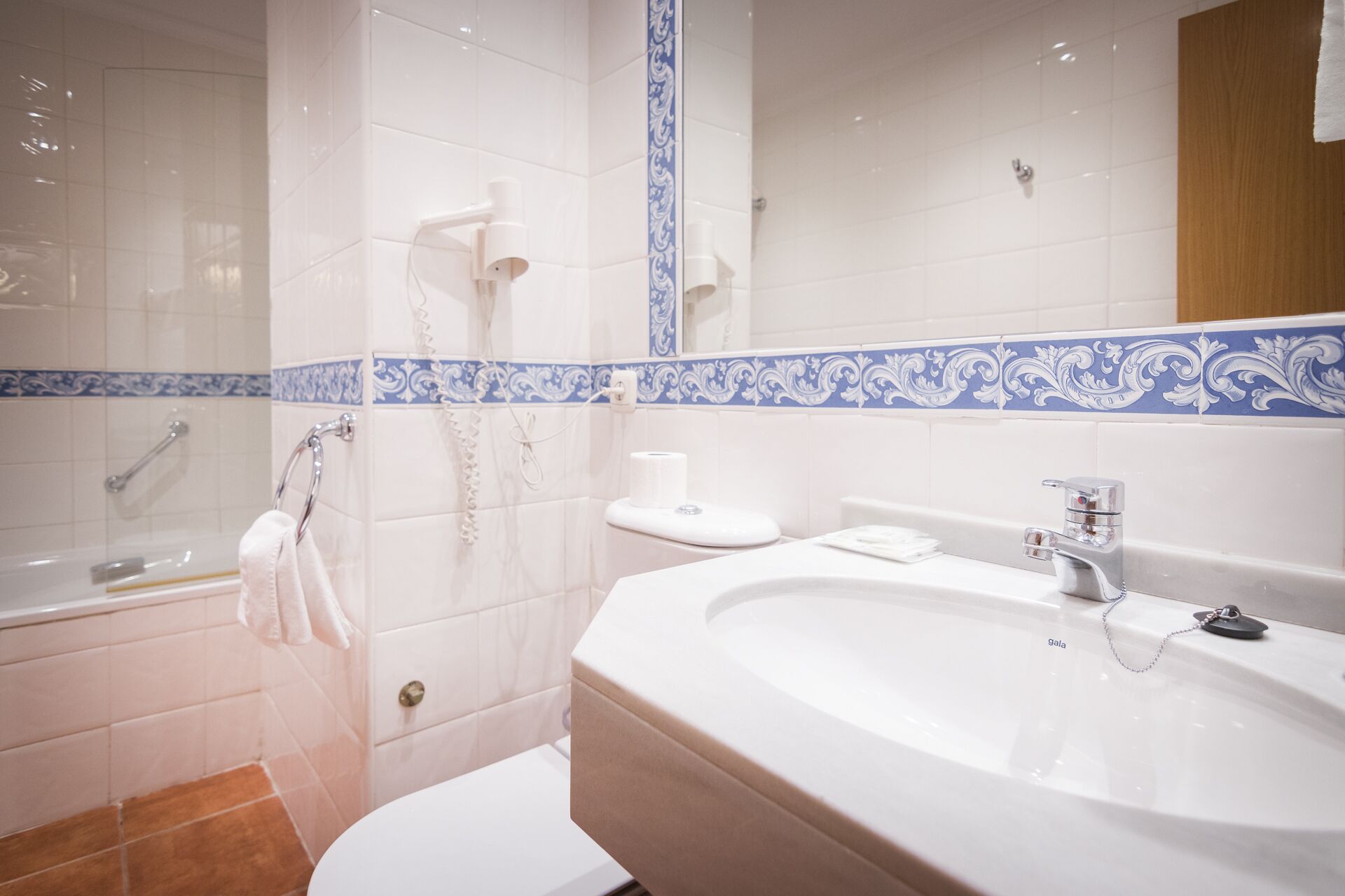 A modern bathroom with a large sink, a shower, and a toilet.
