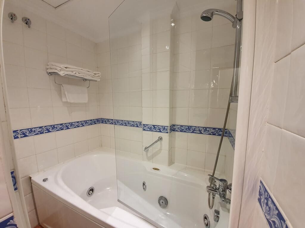 Ein Badezimmer mit einer großen Badewanne, einer Duschkabine und einem Handtuchhalter mit gefalteten Handtüchern.