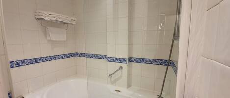 Ein Badezimmer mit einer großen Badewanne, einer Duschkabine und einem Handtuchhalter mit gefalteten Handtüchern.