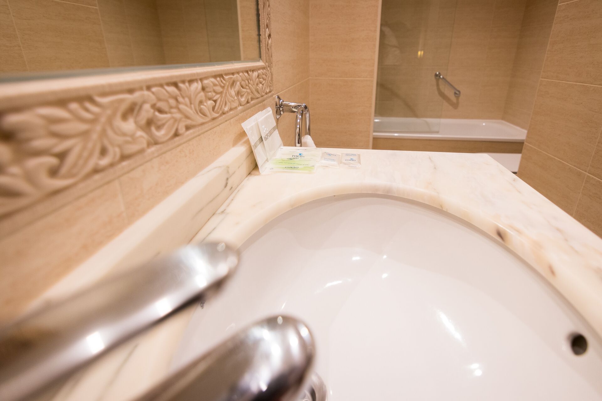 A bathroom with a marble sink, a mirror, and a shower area.