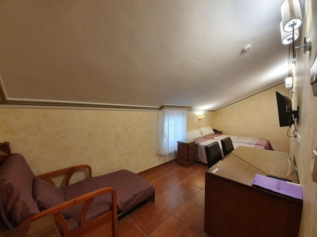 A small, compact room with a bed, a desk, and a chair.