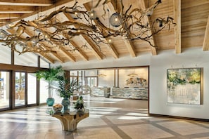 A spacious lobby with a wooden ceiling, a reception desk, and a large window.