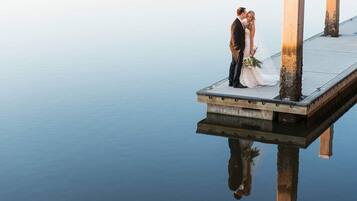 A couple standing on a dock extending over water.