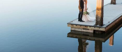 A couple standing on a dock extending over water.