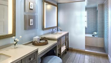 A bathroom with two sinks, a large mirror, a window, and a shower area.