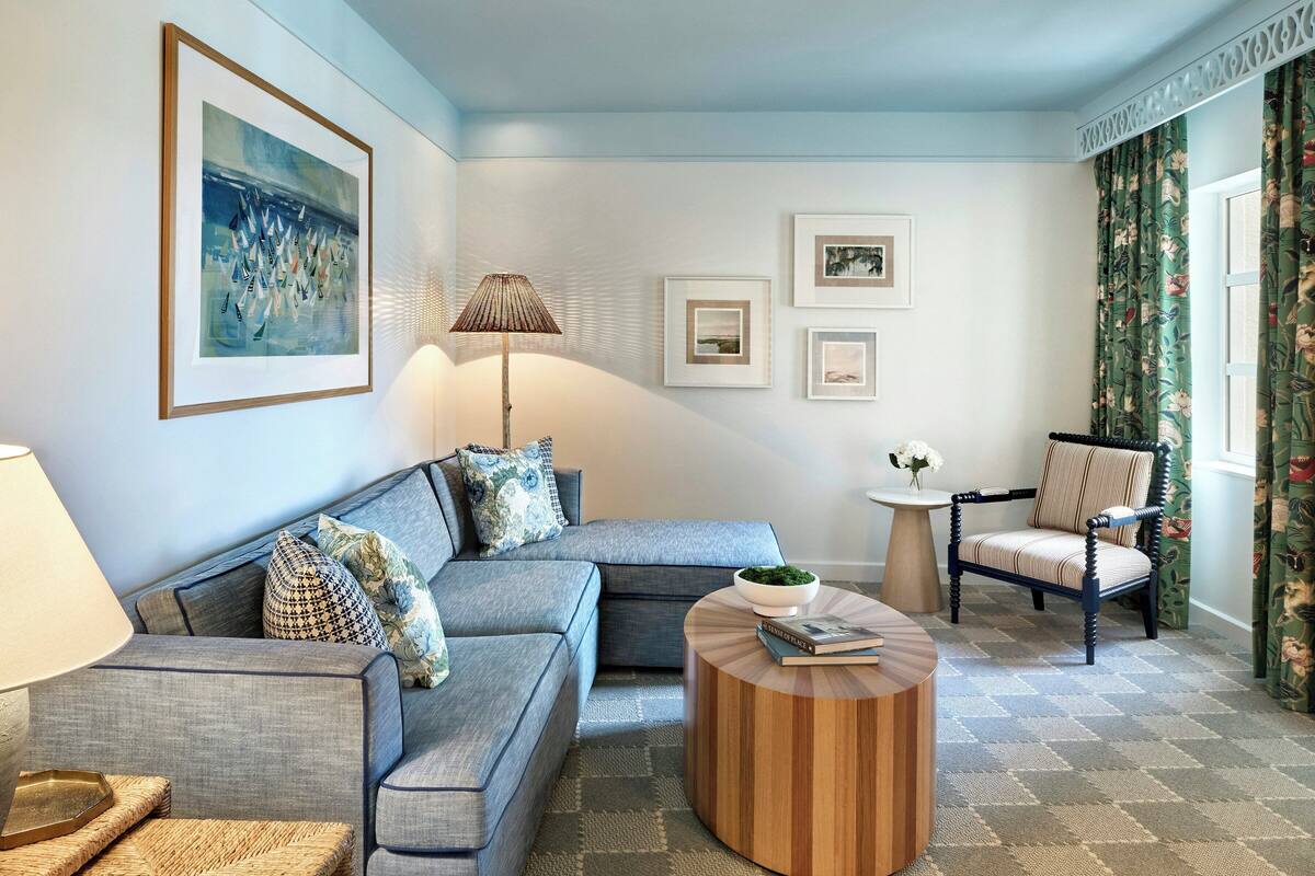 A living room with a sectional sofa, a round coffee table, a side table, a chair, and framed pictures on the wall.