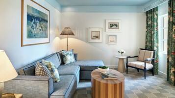 Una sala de estar con un sofá modular, una mesa redonda de centro, una mesita auxiliar, un sillón y cuadros enmarcados en la pared.