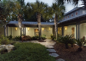 Stroll through the beautifully maintained garden, featuring a paved walkway, a bench for seating, and lush tropical plants.
