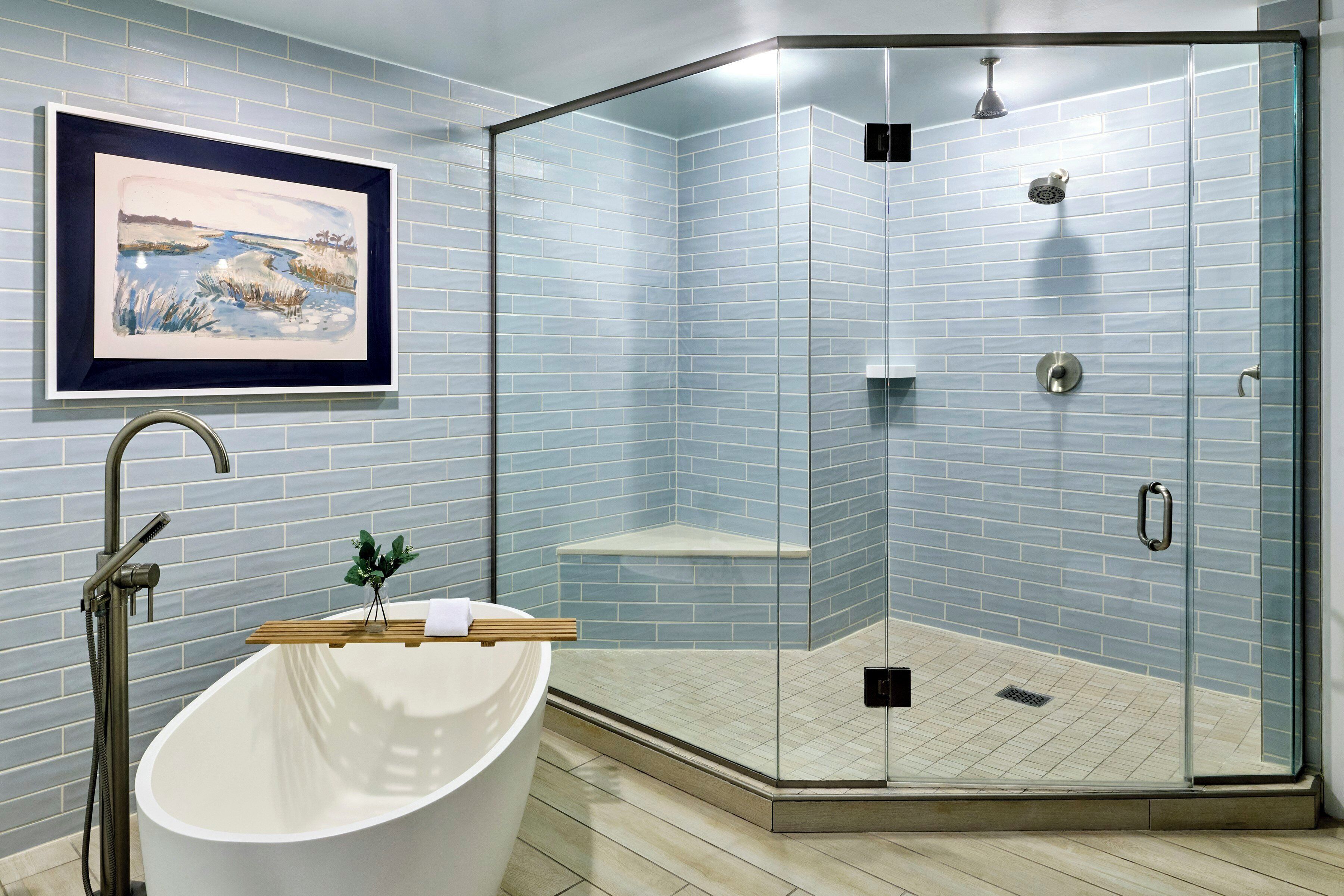 Une salle de bain dotée d’une douche à parois de verre, d’une baignoire sur pieds et d’un tableau représentant un paysage, accroché au mur.