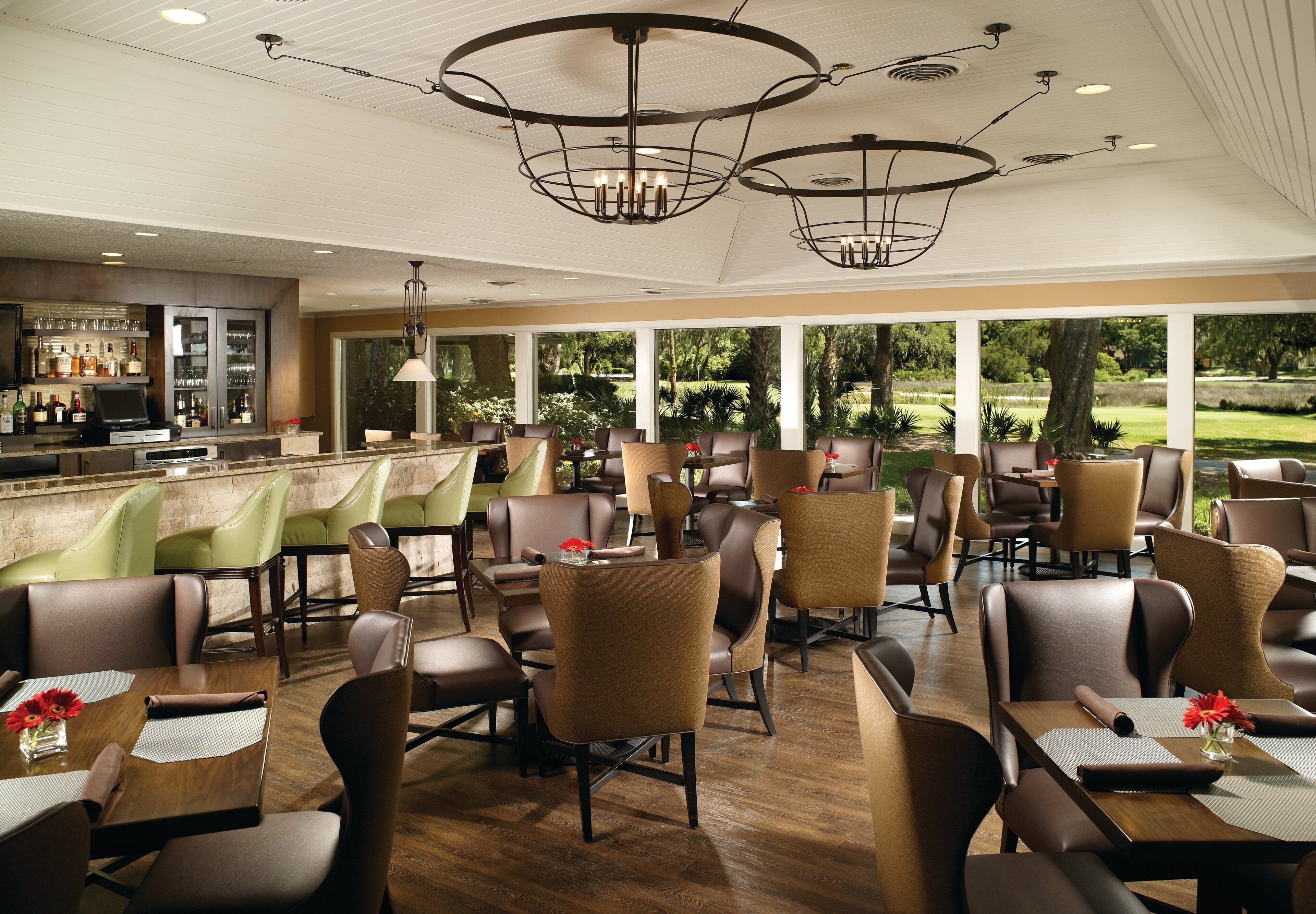 A restaurant with a bar area, multiple seating arrangements, and large windows offering a view of the outdoors.
