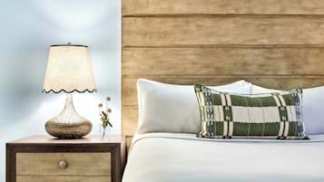 A neatly made bed with a patterned pillow, a bedside lamp, and a wooden nightstand with drawers.