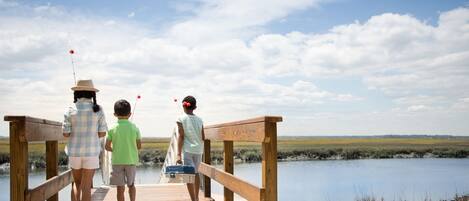 A wooden pier extending over a calm body of water with a clear sky above.