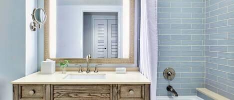 A bathroom with a wooden vanity, a large mirror, a sink, and a shower area with blue tiles.