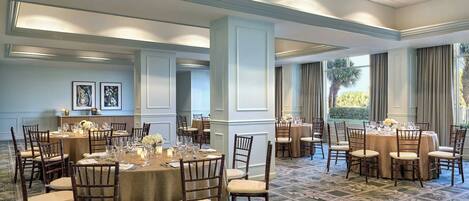 A spacious hotel dining area with multiple round tables set for guests, featuring elegant table settings and comfortable chairs.