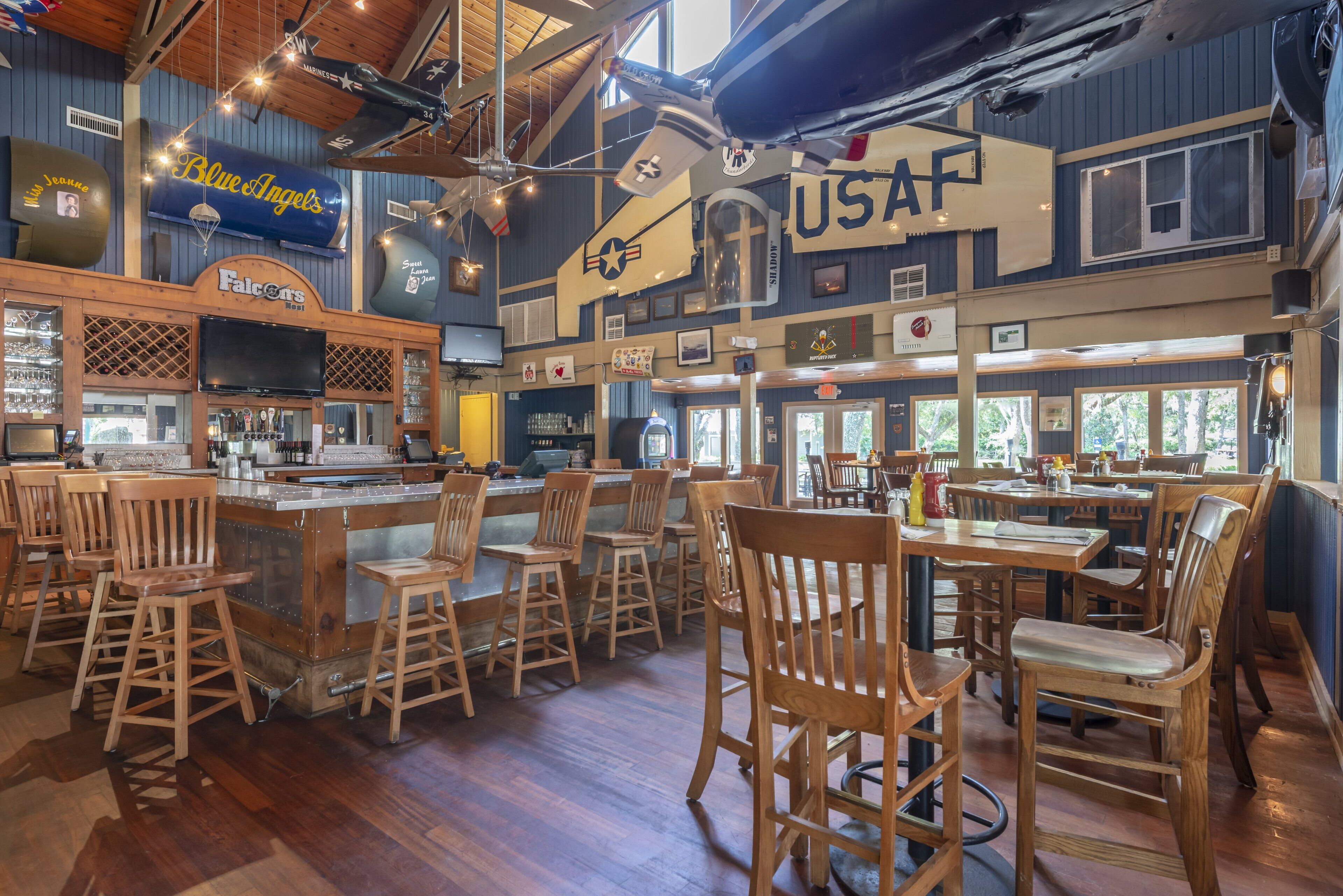 A bar with wooden chairs and a bar counter, a USAF sign, and a vintage airplane.