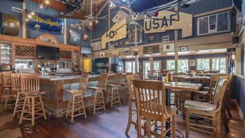 A bar with wooden chairs and a bar counter, a USAF sign, and a vintage airplane.