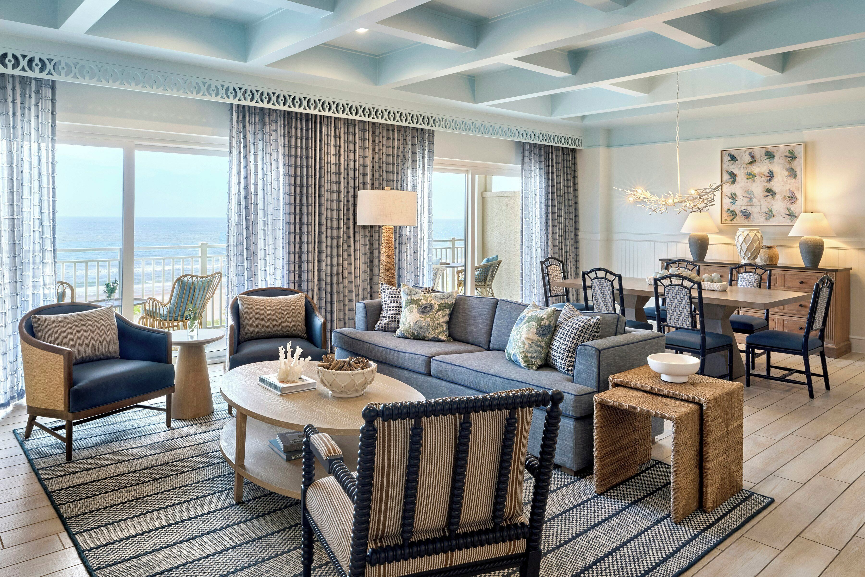 A spacious living room with a large sofa, armchairs, a coffee table, and a dining area with chairs and a table.