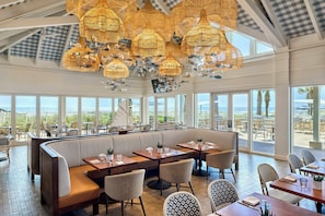 A restaurant with a high ceiling, large windows, and a view of the ocean. - Omni Amelia Island Resort & Spa (Fernandina Beach)