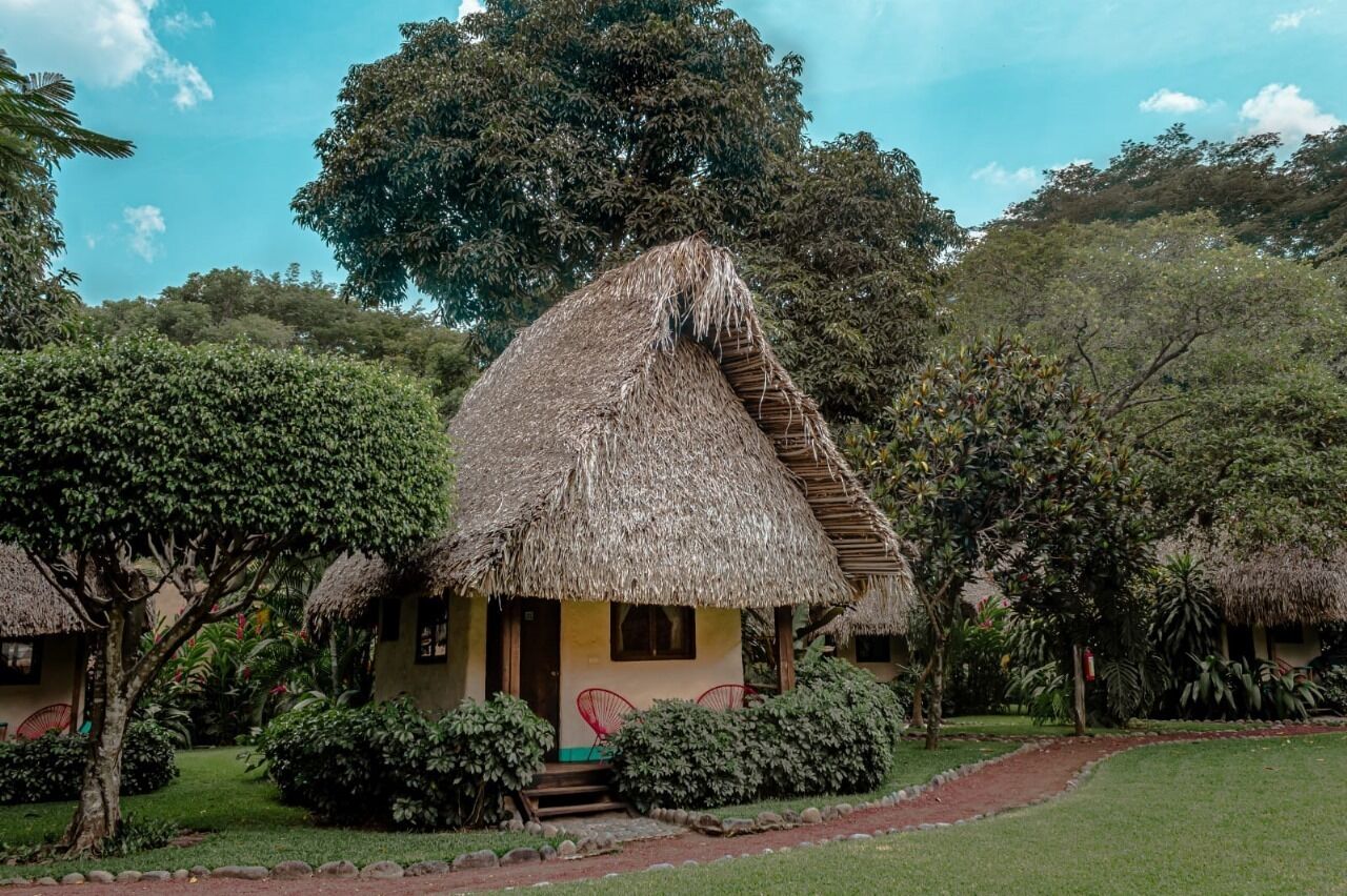 Uma cabana com telhado de palha, um pequeno alpendre e degraus que levam à entrada.