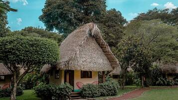 Uma cabana com telhado de palha, um pequeno alpendre e degraus que levam à entrada.
