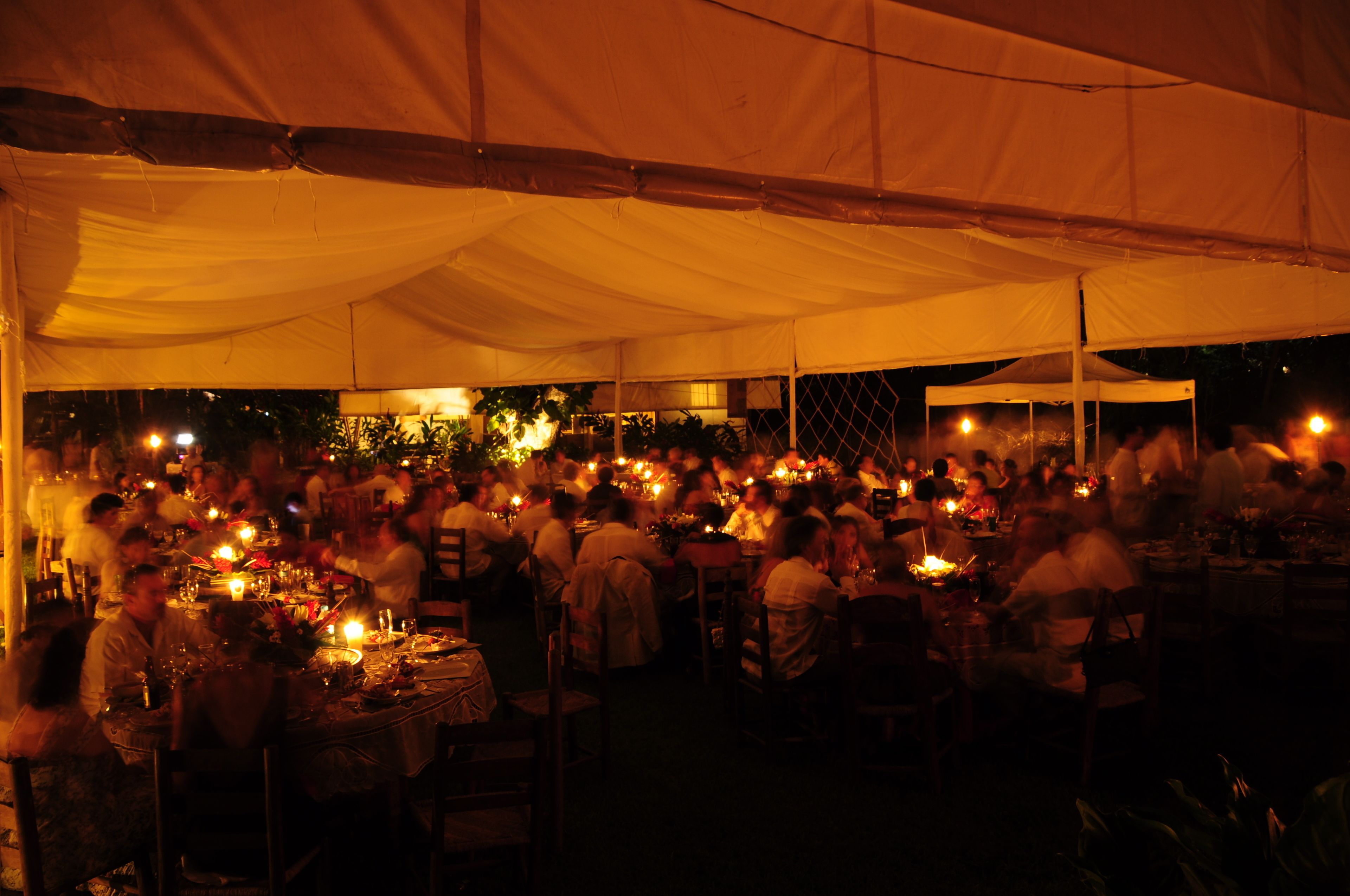 A tented outdoor dining area with tables set for multiple guests, under a canopy.