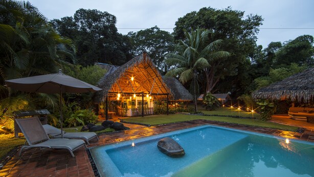 A swimming pool with lounge chairs and a thatched-roof structure. - Picocanoa Rodavento (Jalcomulco)