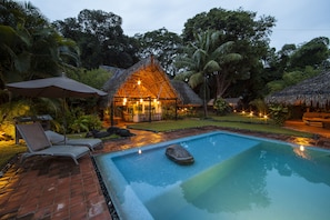 A swimming pool with lounge chairs and a thatched-roof structure. - Picocanoa Rodavento (Jalcomulco)