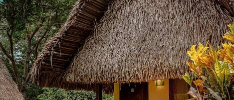 A thatched-roof structure with a wooden door and steps leading to a covered entrance.