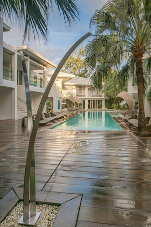 Una piscina al aire libre, sombrillas, sillones reclinables de piscina