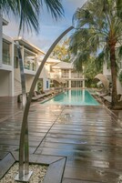 Una piscina al aire libre, sombrillas, sillones reclinables de piscina