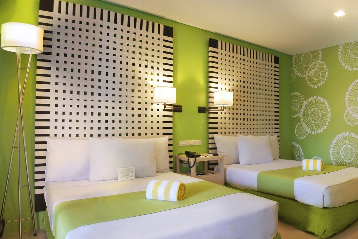 Ein Hotelzimmer mit zwei Betten, einem Schreibtisch mit Stuhl, einem Fernseher und einer Wanddekoration.