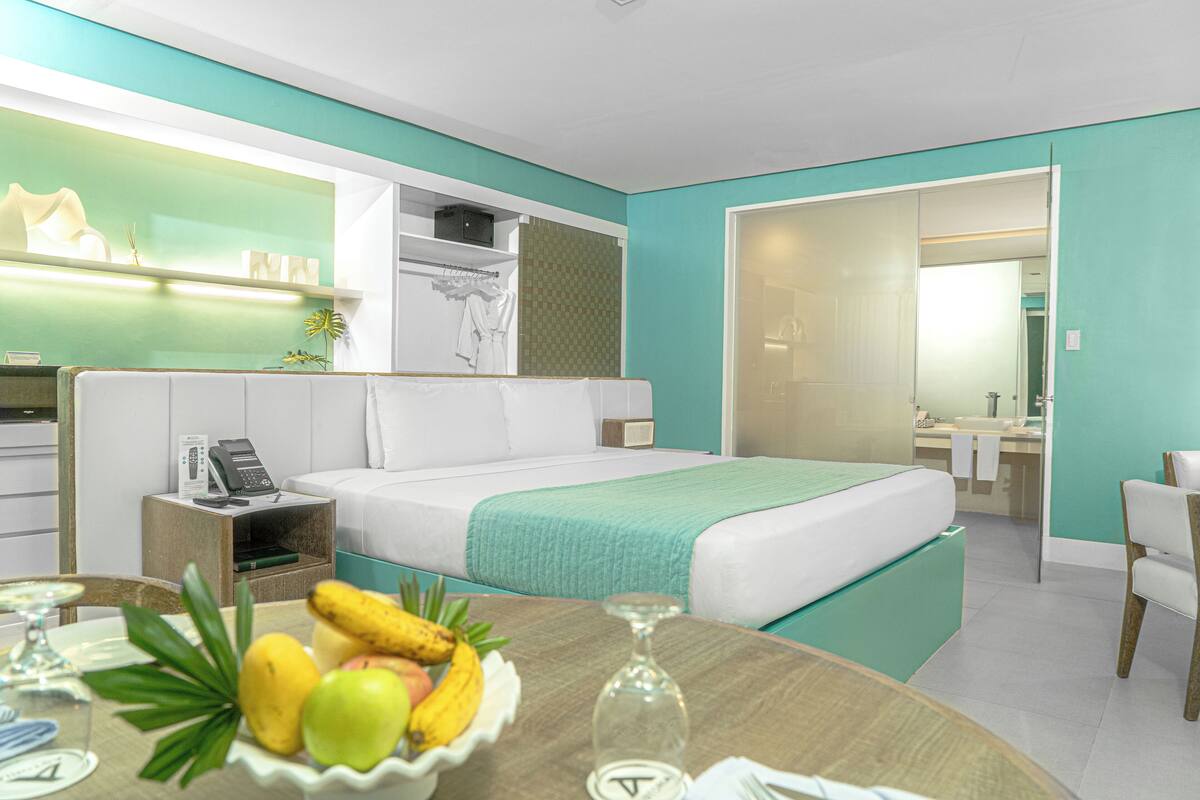 Ein modernes Hotelzimmer mit einem Bett, einem Nachttisch und einer Obstschale.