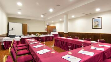 A conference room with tables set for meetings, equipped with microphones, nameplates, and water glasses.