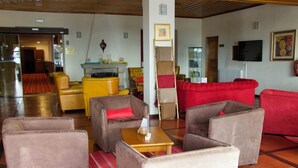 Een hotel lobby met leren banken, een houten bijzettafeltje en een rode bank.