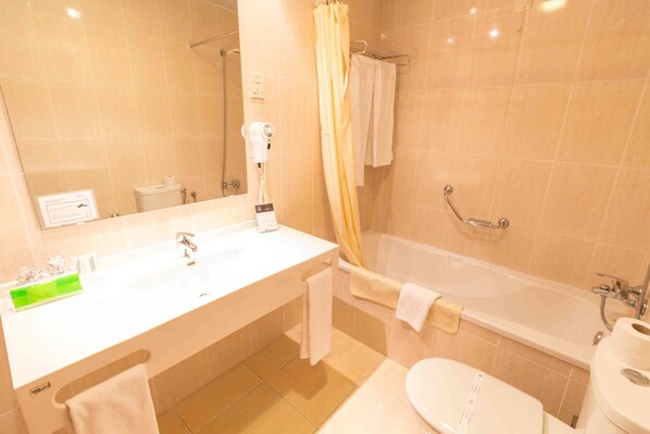 Un baño con lavamanos, inodoro, bañera y secador de pelo.