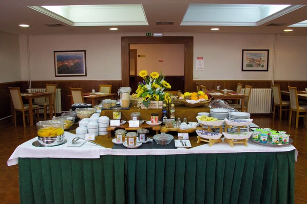 A buffet setup with various food items and beverages, arranged on a table with a green tablecloth.