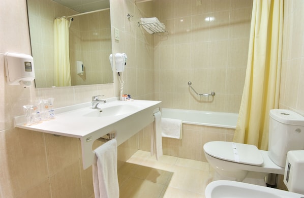 A bathroom with a sink, mirror, towel rack, shower, toilet, and a hand dryer.