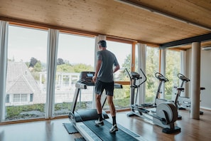 A gym with a treadmill, stationary bikes, and a rowing machine.