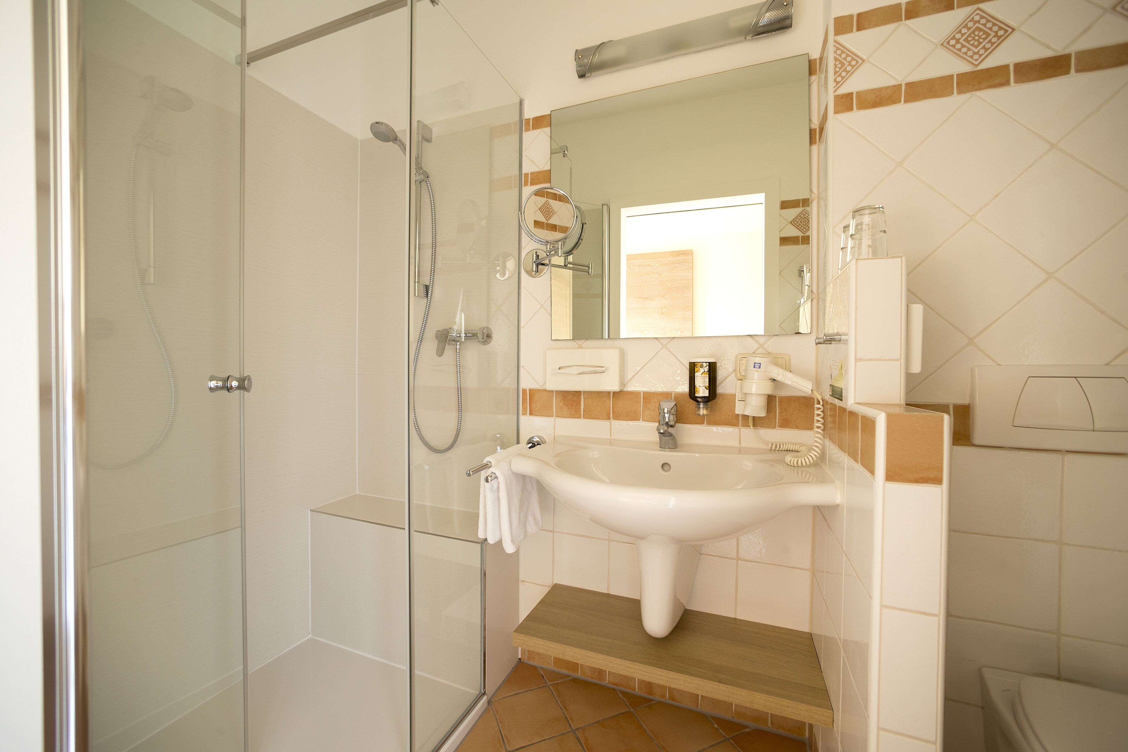 A modern bathroom with a glass-enclosed shower, a white sink, and a mirror above it.