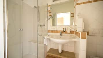 A modern bathroom with a glass-enclosed shower, a white sink, and a mirror above it.