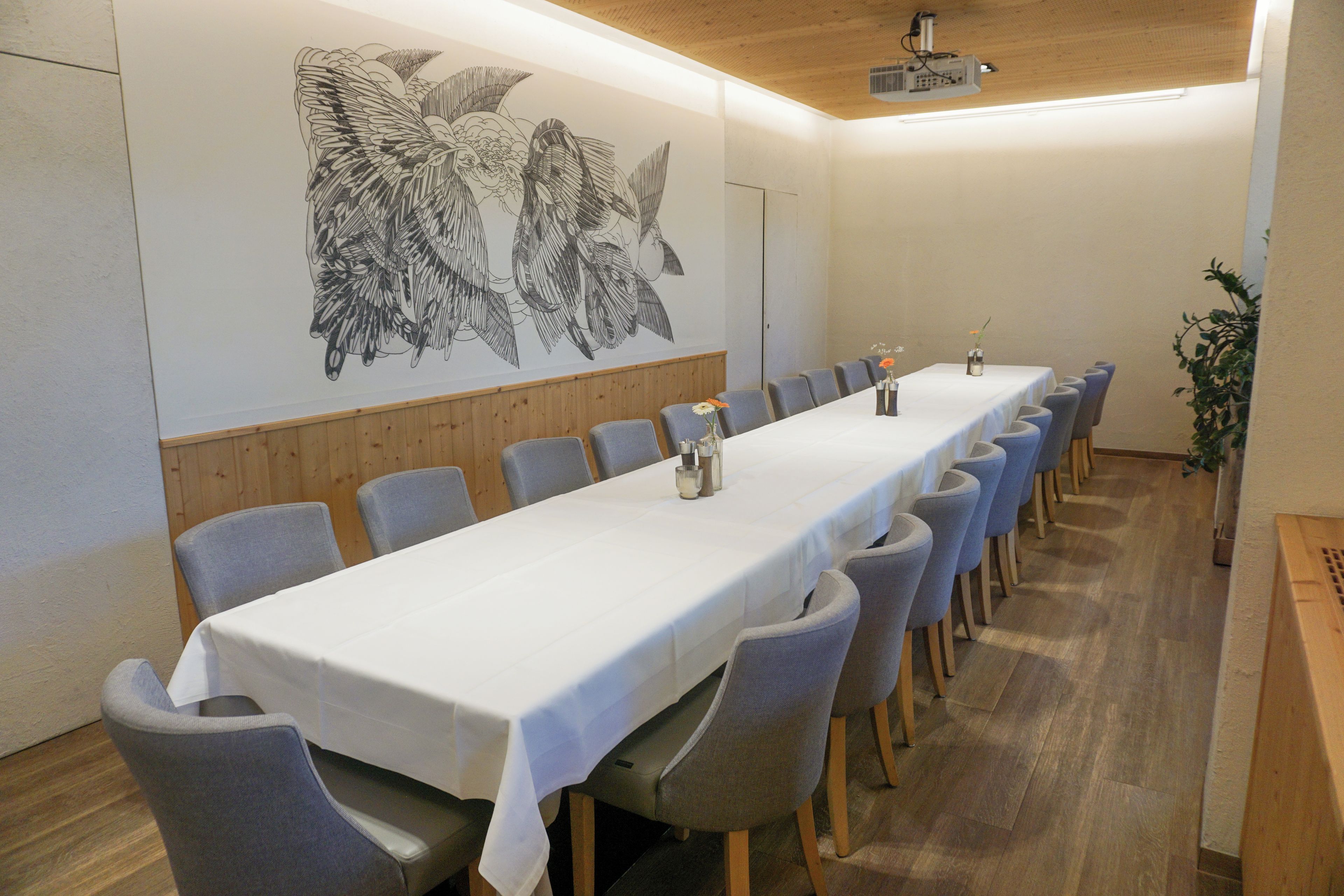 A conference room with a long table, chairs, and a projector.